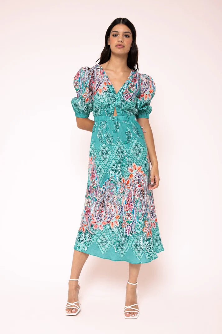 Melody Cut-Out Midi Dress Introducing the Melody Cut Out Midi Dress by Kachel—a striking showstopper featuring voluminous sleeves and intricate front and back cut-out details. Its subtle border paisley print is a wardrobe essential, effortlessly elevating your style.
